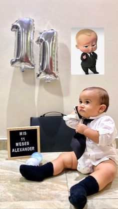 a baby sitting on the ground next to some balloons