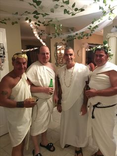 three men dressed in white standing next to each other with beer bottles and leis around their necks