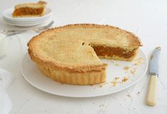 a piece of pie on a plate next to a knife and fork with another slice missing