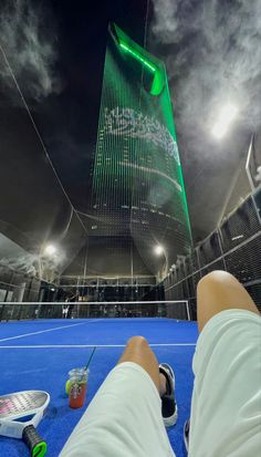 a person laying down on a tennis court with their feet propped up in the air