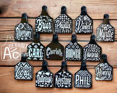 twelve black and white ceramic bottle tags with the names of each type on them hanging from a wooden wall