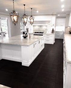 a large kitchen with white cabinets and an island in front of the stove top oven