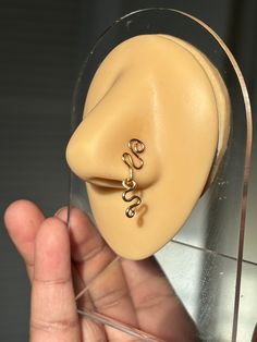 a person holding a fake ear with two rings on it's sides and a nose ring attached to the end