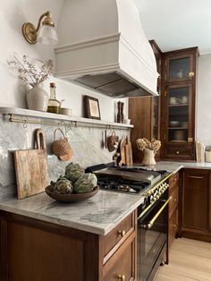 a kitchen with marble counter tops and wooden cabinetry, along with an oven hood