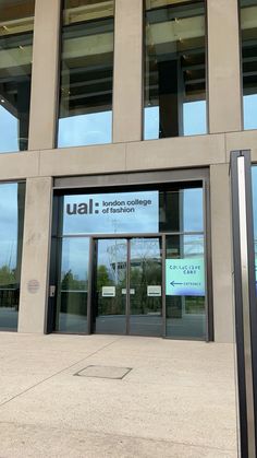 an entrance to a building with glass doors and signage on the front door that reads ual london college of technology