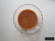 a glass bowl filled with sauce on top of a white table