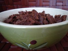 a green bowl filled with brownies on top of a wooden table