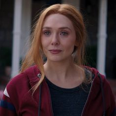 a close up of a person wearing a red hoodie and looking at the camera