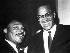 black and white photograph of two men in suits smiling at the camera with one man wearing glasses