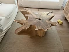 a wooden table sitting on top of a carpeted floor next to a white couch