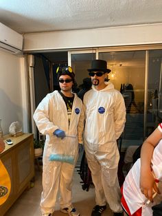 two men in white suits and black hats standing next to each other