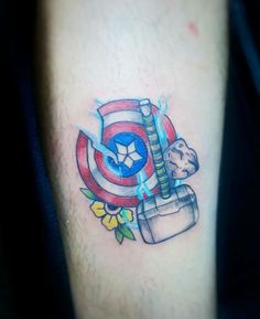 a tattoo on the leg of a man with a captain america shield and flowers around it