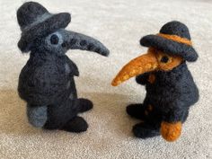 two small stuffed animals wearing hats and sitting on the floor next to eachother