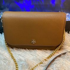 Tory Burch Emerson Chain Wallet Leather Cross Body Bag Color: Moose (Brown) Tory Burch Emerson Chain Wallet Leather Cross Body Bag Features: 8 Credit Card Slots, One Zip Compartment, Gold-Tone Hardware Removable Chain/Leather Shoulder Strap With Approx. 22" Drop Measures Approximately: 7.5" L X 5.5" H X 2.25" W Formal Tan Rectangular Wallet On Chain, Elegant Gold Wallet On Chain For Everyday, Tan Leather Wallet On Chain For Everyday Use, Classic Tan Wallet On Chain For Formal Occasions, Classic Tan Wallet On Chain For Everyday Use, Classic Gold Wallet On Chain For Travel, Gold Leather Wallet On Chain For Everyday, Gold Crossbody Wallet On Chain For Everyday Use, Everyday Gold Leather Wallet On Chain