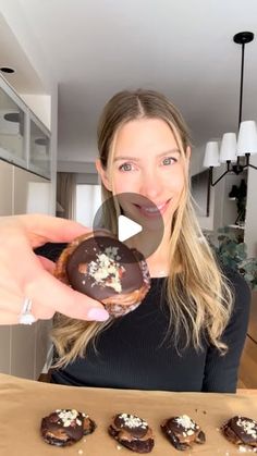 a woman holding up a chocolate covered doughnut