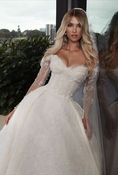 a woman in a white wedding dress standing next to another woman wearing a long veil