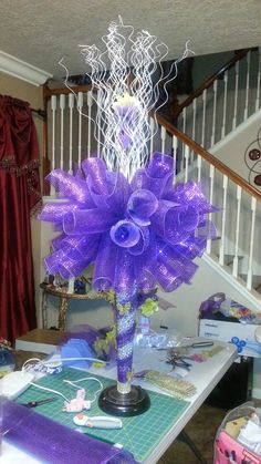 a purple centerpiece sitting on top of a table in front of a stair case