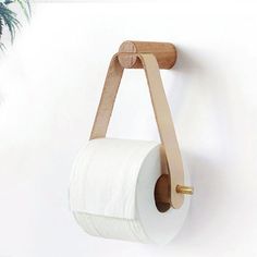 a white toilet paper roll hanging on a wall with a wooden holder attached to it