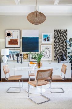 a dining room table with chairs and pictures on the wall in the backround