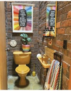 a bathroom with a toilet, sink and bathtub next to a brick wall that has posters on it