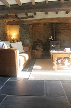 a living room filled with furniture and a fire place next to a wall mounted wood burning stove