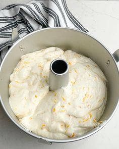 a white cake in a pan with orange sprinkles on the top and an empty cup next to it