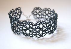 a close up of a black lace bracelet on a white surface with the word love written across it