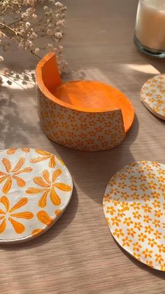 four orange and white plates sitting on top of a table next to a glass vase