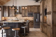 an image of a kitchen setting with wooden cabinets and bar stools in the center