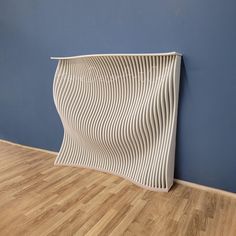 a white sculpture is on the floor next to a blue wall and wooden floors in an empty room