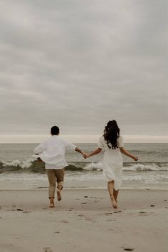 two people running on the beach holding hands