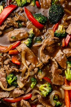 beef and broccoli stir - fry in a skillet with red peppers, onions, carrots, and mushrooms