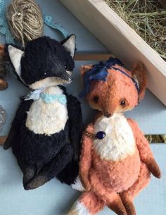 two stuffed animals sitting next to each other on top of a wooden box with twine