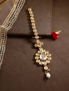 a gold necklace with pearls and a rose on the side, sitting on a brown surface