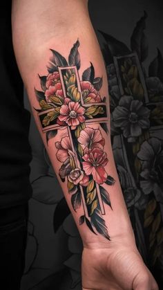 a cross with flowers on it and leaves around the cross is shown in this tattoo design