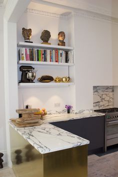 a kitchen with marble counter tops and stainless steel appliances, along with bookshelves