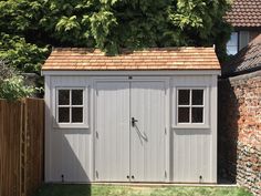 a white shed sitting next to a wooden fence