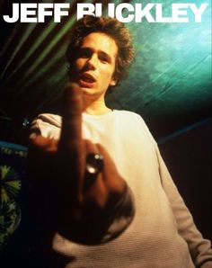 a man standing in front of a green light pointing to the side with his finger