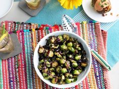 a white bowl filled with brussel sprouts on top of a colorful place mat