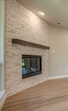 an empty living room with a fireplace and hard wood floors