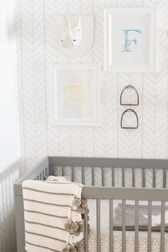 a baby's crib in a white and gray nursery with pictures on the wall