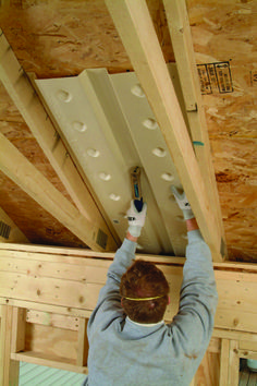 a man working on the ceiling in a house under construction with wooden beams and insulation tape