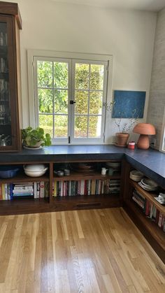 a kitchen with wooden floors and cabinets filled with books