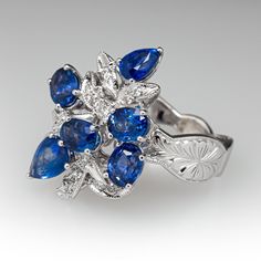 This captivating cluster style ring is accented with four (4), prong set, oval mixed cut natural sapphires and two (2), prong set, pear mixed cut natural sapphire. The sapphires are bordered with two (2), prong set, round brilliant cut diamonds and fourteen (14), bead set, round brilliant/single cut diamonds, bordered with milgrain edging. Engraved details accent the shoulders of the shank. The ring measures 22.6mm at the top, rises 9.8mm above the finger, tapering to 3.8mm wide and 1.3mm thick at the base of the shank. This ring is currently as size 6.5. Elegant Pear-shaped Multi-stone Sapphire Ring, Marquise Sapphire Ring With Rose Cut Diamonds, Pear-shaped Sapphire Multi-stone Ring, Fine Jewelry Pear-shaped Sapphire Ring, Pear-shaped Multi-stone Sapphire Ring For Anniversary, Blue Sapphire Diamond, Bead Set, Diamond Cluster Ring, Natural Sapphire