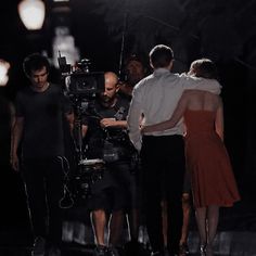 a group of people standing next to each other in front of a camera on a street