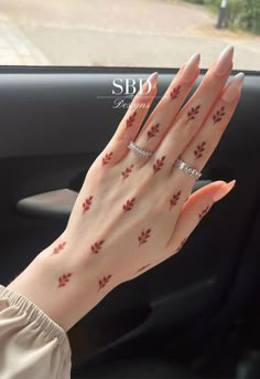 a woman's hand with red leaves on it and her nails in the air