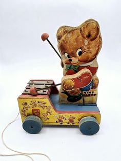 an old toy radio with a teddy bear on it's side and a string attached to the top