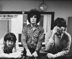 three young men sitting at a table in front of a computer monitor, one with his hands on his face