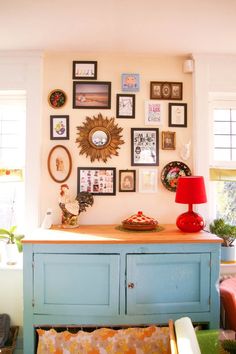 a living room with pictures on the wall and a blue cabinet in front of it