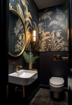 a bathroom with a toilet, sink and wallpaper in black and gold color scheme